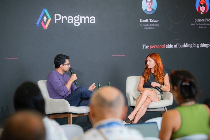 A man and a woman sit on stage at the Pragma conference in Lisbon, with the backdrop displaying "The personal side of building big things" alongside their names, Kartik Talwar (Co-Founder ETHGlobal) and Simona Pop, as he speaks into a microphone during what appears to be a fireside chat interview.