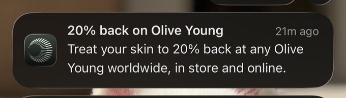 A notification banner reads "20% back on Olive Young — Treat your skin to 20% back at any Olive Young worldwide, in store and online," timestamped 21 minutes ago. The user's reply jokes that they were "kinda late" catching the offer, suggesting they just saw the notification despite the deal having been available earlier.