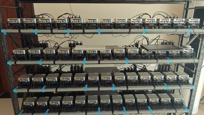 Multiple metal racks filled with rows of identical crypto mining or computing hardware devices connected by numerous cables.