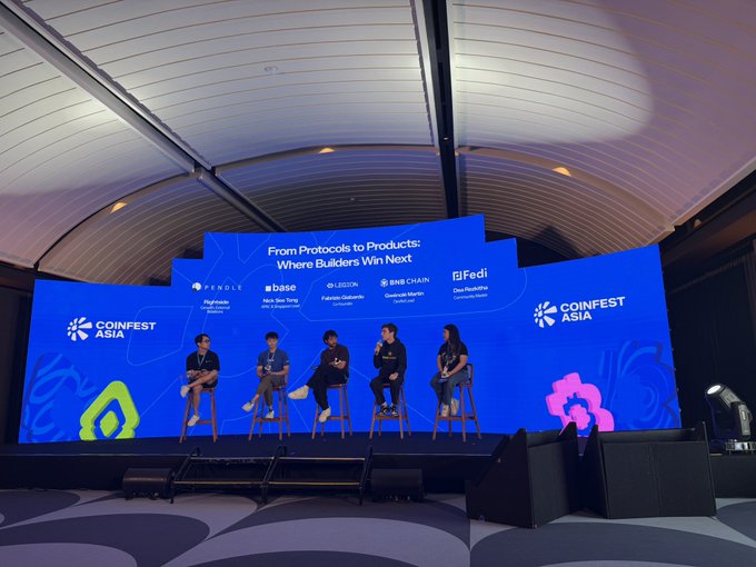 A panel of five people sits on stools at the 'COINFEST ASIA' conference, set against a large blue screen reading "From Protocols to Products: Where Builders Win Next" with logos for Pendle, Base, LZ, and Fedi.