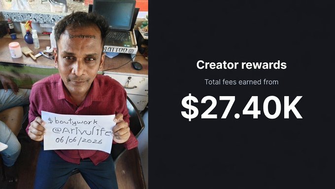 The image features an Indian man holding up a sign that says "Creator rewards" with his face visible. The man appears to be smiling for the camera, and there are other people present in the background who seem to be engaged in conversation or observing something else. The main focus of the image is on the man's sign and the message it conveys about the creator rewards.