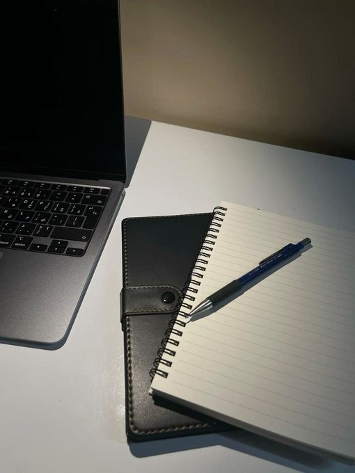 A laptop sits beside an open black notebook with a pen resting on its lined pages, ready for planning. The blank notebook symbolizes fresh preparation, visually capturing the "New week, New opportunity, New plan" mindset for traders.