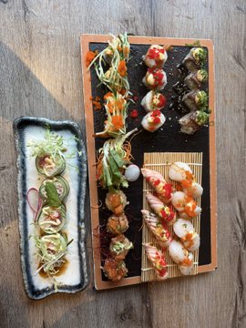 iced tea and sushi rolls are arranged on a wooden table, with the sushi rolls featuring red fish and white rice as the main focus.