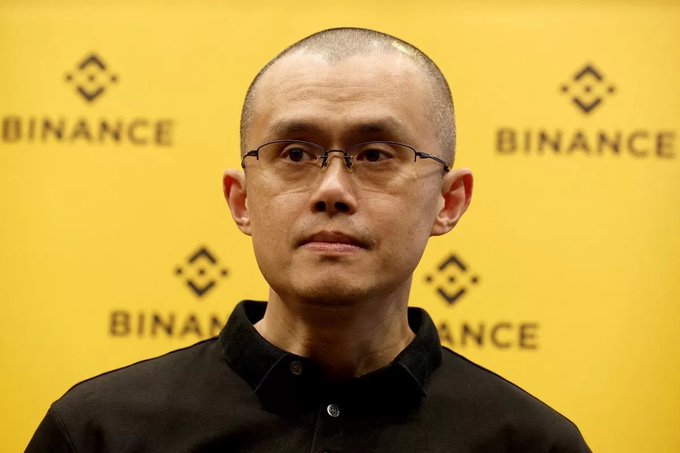 Changpeng Zhao, founder of Binance, stands before a backdrop of the company's logo and name. The image relates to his proposal to freeze Satoshi Nakamoto's dormant Bitcoin holdings to protect them from potential cyberattacks.