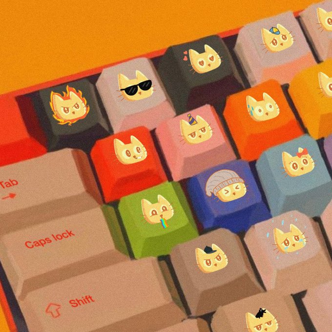 A close-up of a colorful mechanical keyboard featuring custom keycaps with cute cat face designs in various expressions and accessories like sunglasses and hats.