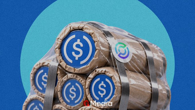 A graphic illustration showing bundles of USDC stablecoin wrapped in bands, stacked together against a blue and teal circular background, watermarked with 'C. Media'.