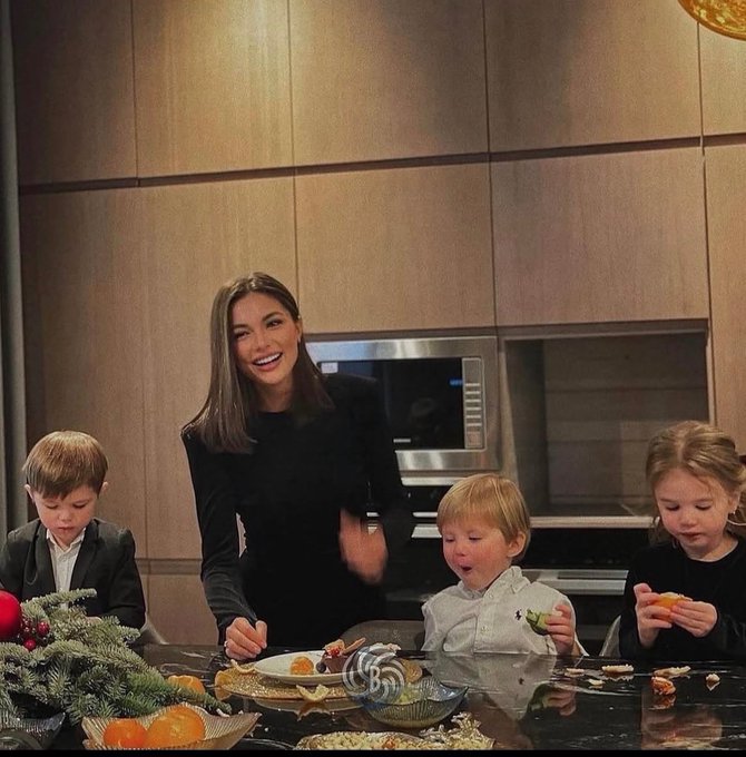 The image shows a woman, likely a mother or an older sister, sitting at a dining table with her children. They appear to be enjoying their time together during a meal. The table has various food items such as bowls of fruit, including oranges, and plates of food like cake. A microwave is also visible in the background.

The post includes text that reads: "“Mommy why are we so rich?” - Because your dad was never panicked selling the dip". This statement seems to be a playful comment about their family's financial situation or the mother's role as a provider for her children, suggesting that they may have been well-off and could afford nice things like food at restaurants.

The image captures a moment of togetherness between the woman and her children while enjoying a meal in a cozy setting with wooden cabinets and a dining table.