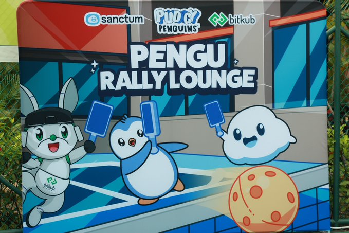 A colorful sign for 'PENGU RALLY LOUNGE' featuring cartoon characters, including a robot and penguins playing on a court, with logos for 'sanctum', 'PUDG PENGUINS', and 'bitkub'.
