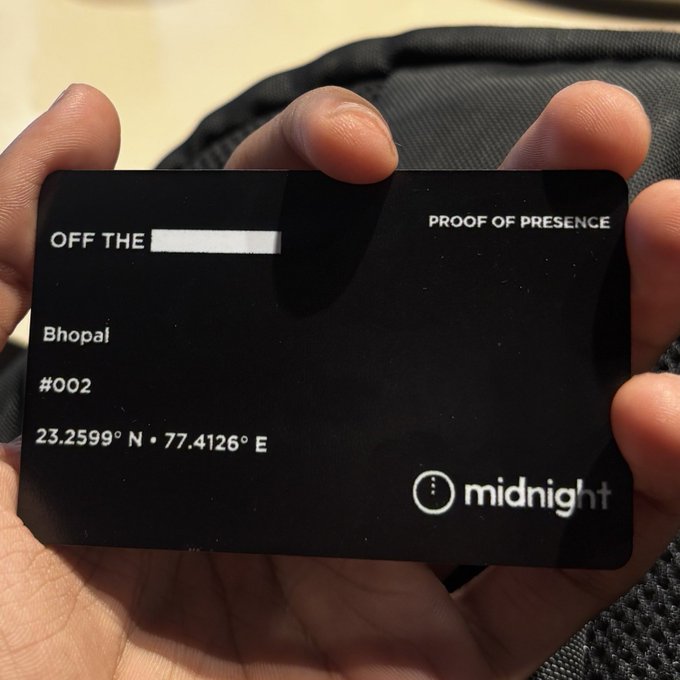 A hand holds a black "Midnight" proof-of-presence card #002 labeled "OFF THE [redacted]," referencing "Bhopal" with coordinates 23.2599° N, 77.4126° E, illustrating the concept of revealing location while keeping personal identity private.