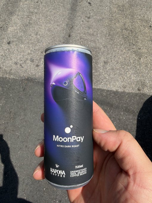 A hand holding a can of MoonPay Nitro Dark Roast coffee in a purple and black can featuring a moon graphic, produced by Raposa Coffee in collaboration with Pu'ukalani.