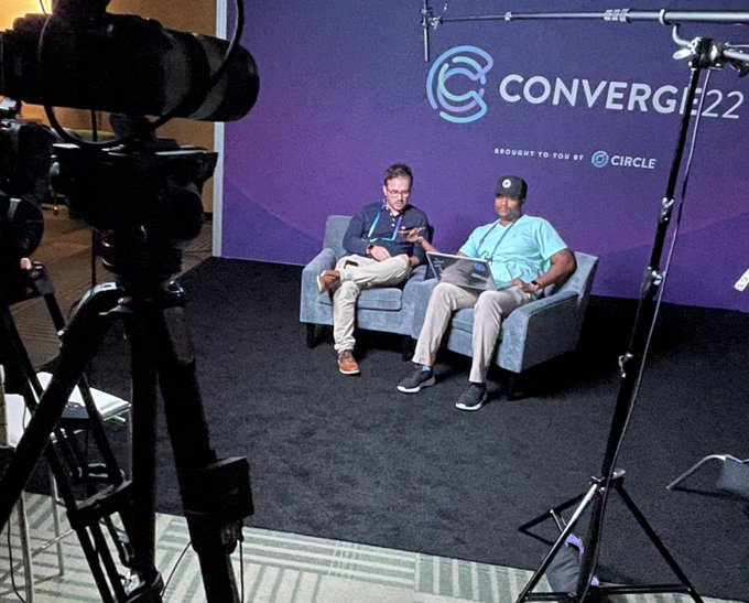 Behind-the-scenes of a media interview at CONVERGE22 (brought to you by Circle), with two men seated in chairs being filmed by a professional camera setup.