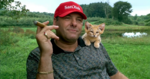 A humorous photoshopped image showing Nicolas Maduro wearing a red 'SANDALS' cap with a small ginger cat resting on his shoulder while he makes a pinching gesture with his hand.