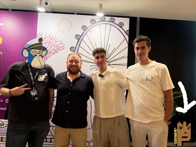 Four men pose for a photo in front of a colorful backdrop featuring a Bored Ape Yacht Club logo, with the handle '@stoc' and an arrow drawn on the image.