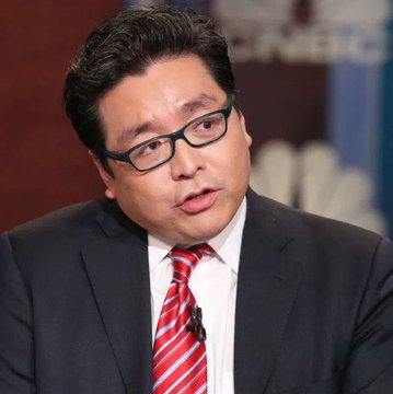 Close-up photo of a man with dark hair and glasses wearing a dark suit, white shirt, and red striped tie, appearing to speak in an interview setting.