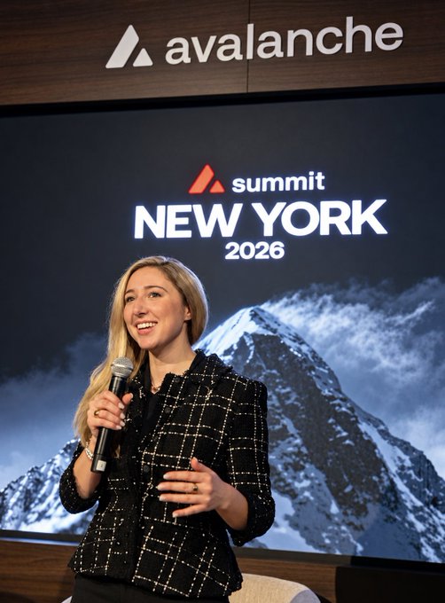 A blonde woman, identified as Olivia Stec (@cryptoreine) from Ava Labs, speaks into a microphone on the Hudson stage at Avalanche Summit New York 2026, with the event's logo and a snowy mountain backdrop displayed behind her.