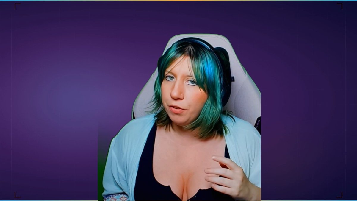 A teal-haired streamer wearing a headset and glasses sits in a gaming chair against a purple background, likely from a video discussing a major LAND announcement in The Sandbox game.