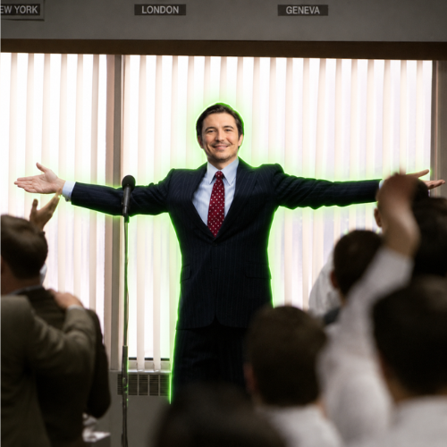 A man in a suit stands with arms outstretched at a podium under a sign with city names including 'LONDON' and 'GENEVA', with a green glow behind him.