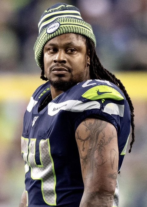 A photo of NFL player Marshawn Lynch wearing his Seattle Seahawks #20 jersey and a beanie, looking toward the camera.