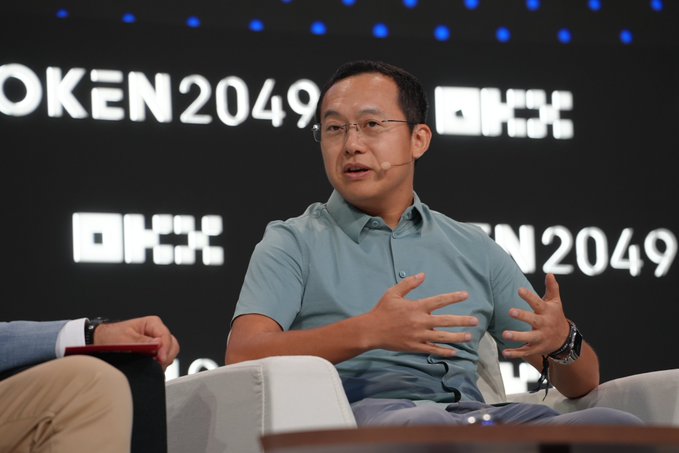 OKX founder Star Xu speaks at the TOKEN2049 conference, gesturing with his hands as he discusses upcoming fundamental changes in finance, including user experiences becoming as instant as messaging or booking a ride.