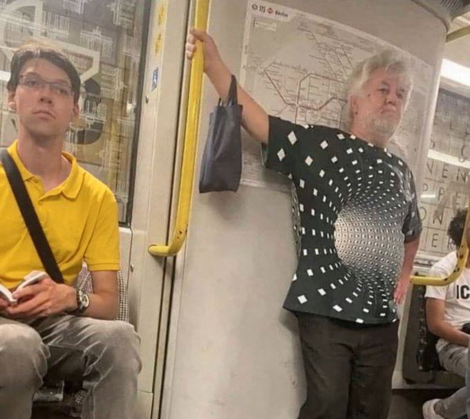 An older gentleman on a subway wears a black shirt with a chart-like design of white squares arranged in a wave pattern, while a man in a yellow polo sits nearby looking up at him. The shirt's pattern humorously resembles a stock chart or data visualization, fitting the caption about looking at charts for too long.

Visible text includes a transit map on the wall and partial letters spelling "MIEN" and "ER" on a sign in the background.