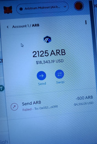 A photo of a computer screen displaying an Arbitrum Mainnet wallet showing a balance of '2125 ARB' ($18,343.19 USD), with a failed send transaction of -500 ARB visible below.