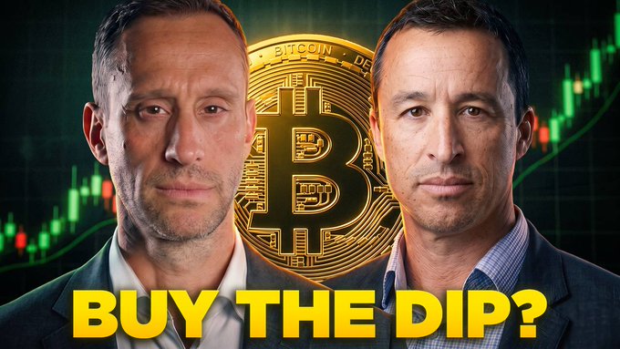 A YouTube thumbnail featuring two men in suits flanking a large Bitcoin graphic, with bold yellow text reading "BUY THE DIP?" overlaid on a green candlestick chart background, promoting a discussion on why the current Bitcoin dip presents a bullish opportunity.