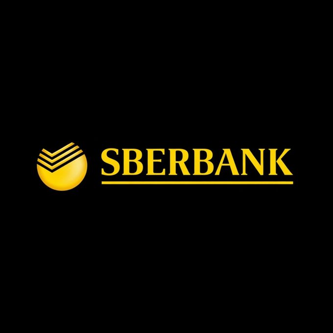 The image displays the Sberbank logo, featuring a yellow sphere with chevron markings alongside the bold yellow "SBERBANK" text on a black background. This logo represents the Russian banking giant mentioned in the news about its plans to accept Bitcoin ($BTC), Ethereum ($ETH), and Tether ($USDT) as loan collateral under new crypto regulations.