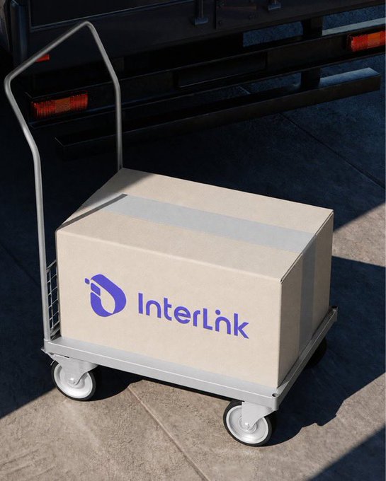 A cardboard box branded with the purple 'InterLink' logo rests on a metal hand truck near the back of a truck, ready for delivery.