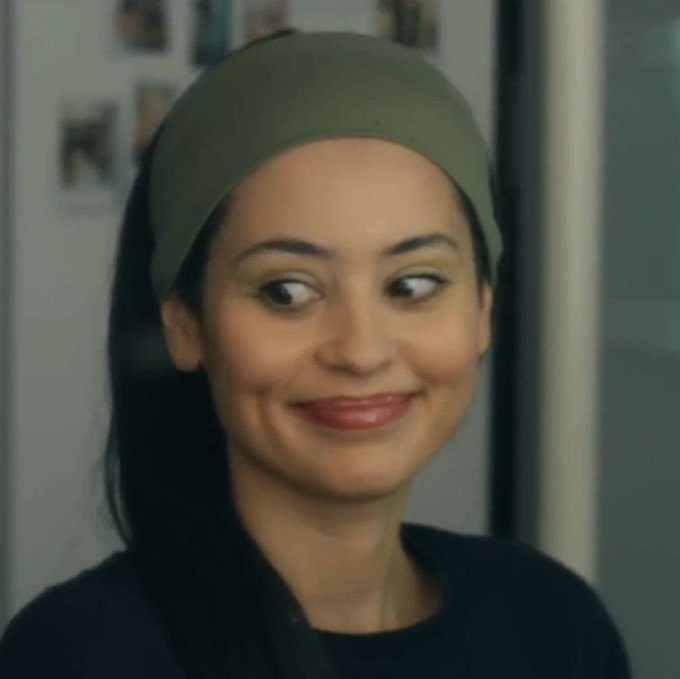 The image shows a woman wearing a green headband and a black top, smiling playfully while looking to the side, with photo prints visible on a refrigerator in the background. The accompanying post appears to be a sponsored promotion for Earno, suggesting the woman is featured as part of an influencer-style endorsement for the platform's rewards program.