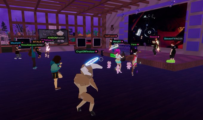 A screenshot from a virtual reality game showing avatars gathered in a club-like room with purple lighting; visible usernames include 'KHIRON#46089', 'Mouth#1', 'RosaAlekseeva#2662', 'BITALK', 'Card#ravel', 'MaryElf', 'Rowsi#1', 'StevenYYn0#235', 'Fenn', and 'CryptoDMnotau'.