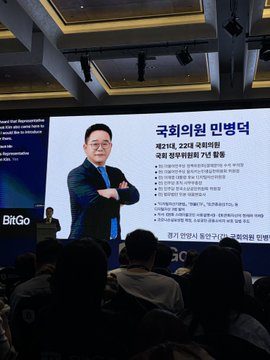 The image shows a presentation at a BitGo event in South Korea, where a man in a suit stands before a large screen titled "국회의원 이병덕" (National Assembly Member Lee Byung-duk), announcing the "제2차" WEB3E policy for the 22nd National Assembly. The caption connects to the speaker's remarks about strengthening the won-pegged stablecoin, focusing on RWA (real-world assets), institutional support for won stablecoins, and increased government funding for blockchain talent development.