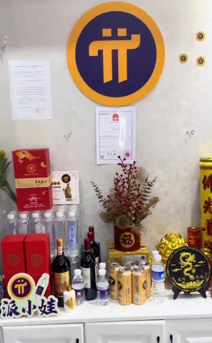 A display of liquor bottles, boxed wines, and decorative items arranged on a counter with a "TT" Pi Network logo on the wall above, watermarked "派小娃".