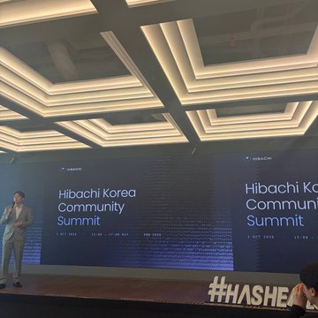 A man stands on stage at the "Hibachi Korea Community Summit," with the event title displayed on a large screen behind him and a glowing hashtag "#HASHEA" visible in the foreground.