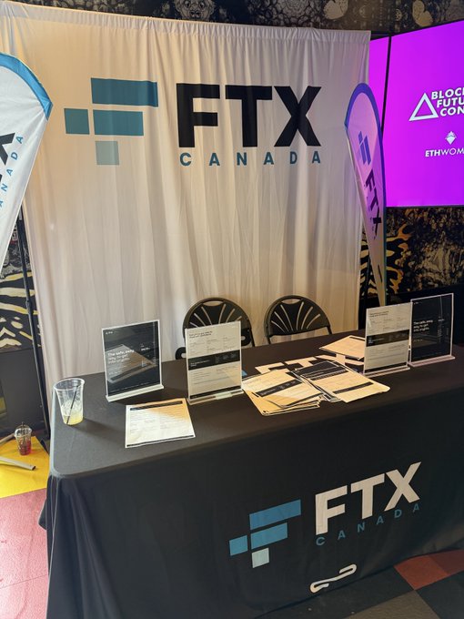 The FTX Canada booth at the Futurist Conference in Toronto features the company's branding prominently on a backdrop and on the table's tablecloth. A screen in the background displays "BLOCKCHAIN FUTURE CON" and "ETHWOMEN".