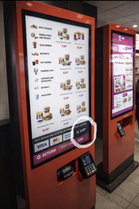 A photo of a self-service ordering kiosk at a fast-food restaurant (likely KFC based on the branding) with a menu showing items like Juicy Chicken, French Fries and Snacks, and Cold Drinks; 'XRP' is circled in white ink on the screen's payment options near Visa/Mastercard logos.
