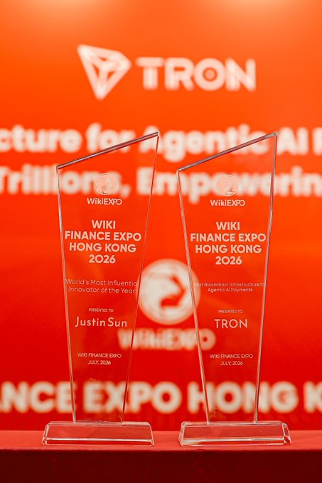 Two awards from Wiki Finance Expo Hong Kong 2026 are displayed: one for "Best Blockchain Infrastructure for Agentic AI Payments" presented to TRON, and another for "World's Most Influential Innovator of the Year" presented to Justin Sun. The awards are positioned in front of a TRON branded backdrop, visually reinforcing the post's message of TRON's recognition.
