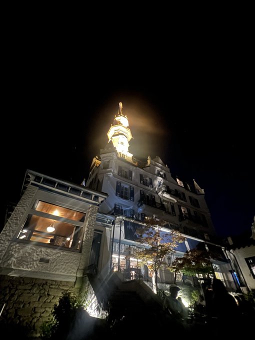 A historic multi-story building with an ornate domed tower rises dramatically against the night sky, illuminated by warm golden lighting that highlights its architectural details, including a stone-faced lower section and decorative railings.

The caption connects to "GN 2/2" likely as the second of two photo entries (2 of 2) capturing the grandeur of this landmark building at night.