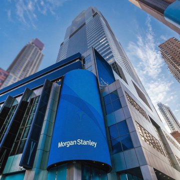 The Morgan Stanley logo is displayed prominently on the exterior of a tall skyscraper against a blue sky, visually representing the financial giant as it expands into cryptocurrency trading through its E*TRADE platform.