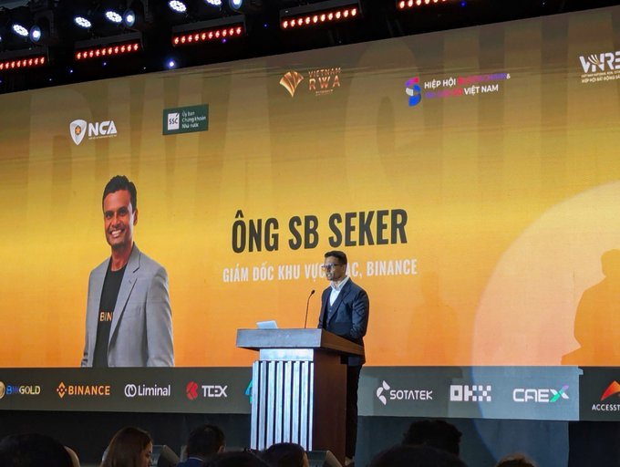 A conference stage where 'Ông SB Seker,' Giám đốc khu vực của Binance (Binance Regional Director), is presenting at the Vietnam RWA event.