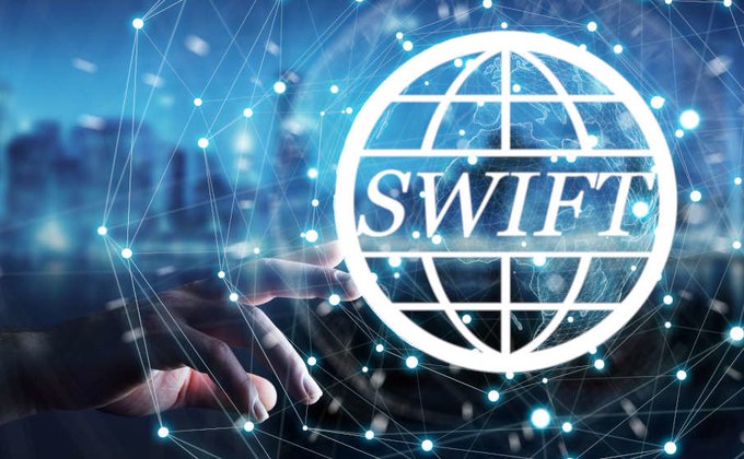 The image shows a glowing hand reaching toward an illuminated SWIFT globe logo set against a futuristic digital network backdrop with city lights. The "SWIFT confirms: 17 banks are now preparing to pilot 'Crypto style' cross-border payments" caption, shown beside the iconic banking network symbol, visually reinforces the post's message about traditional financial infrastructure embracing blockchain-style payment innovation.