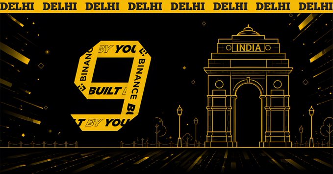 A dark gold and black Binance 'Built by You, By You' promotional graphic featuring Delhi, India landmarks (India Gate) with 'DELHI DELHI DELHI' text banner and Binance branding.