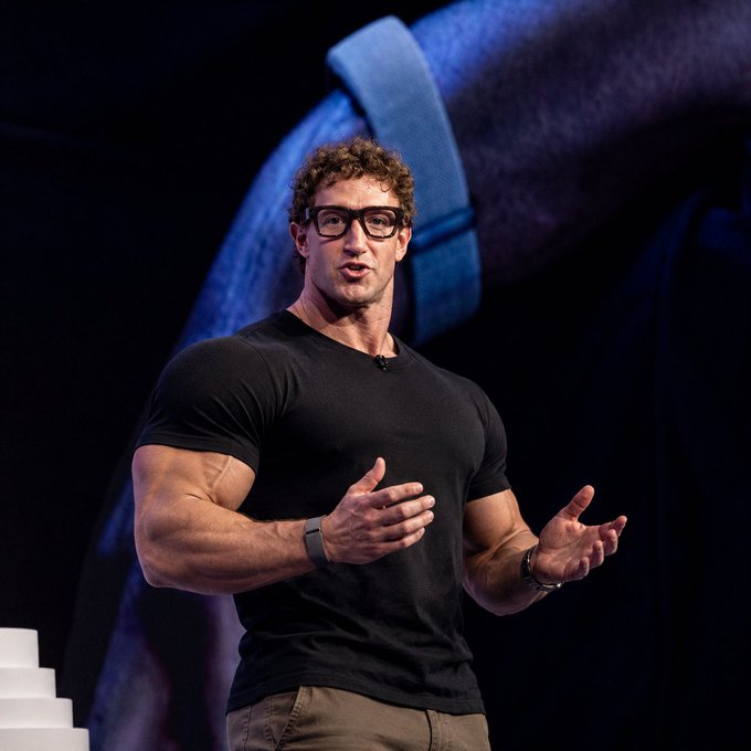 Mark Zuckerberg, sporting his signature black tee and glasses, gestures while speaking on stage against a backdrop featuring a wrist wearing a smartwatch—fitting for a post tagging him as a "Based e/acc Gigachad." The image showcases Meta's CEO in a typical tech-conference setting, aligning with the effusive admiration in the accompanying tweet.
