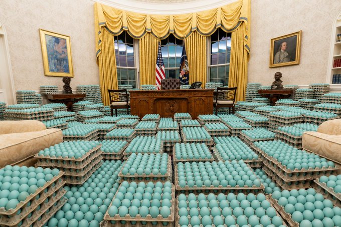 The Oval Office of the White House is flooded with thousands upon thousands of teal-colored eggs filling every inch of the floor, surrounding the Resolute desk beneath the iconic gold curtains—visually linking the everyday staple consumed by 98% of U.S. households with the seat of American governance to suggest eggs are being elevated to a national, blockchain-worthy commodity.