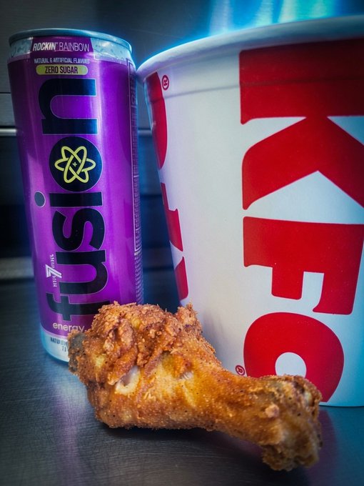 A purple Rockin' Rainbow "FUSION" zero sugar energy drink sits next to a KFC bucket with a crispy fried chicken drumstick in the foreground. The image visually represents the casual pairing referenced in the post about $XPR.