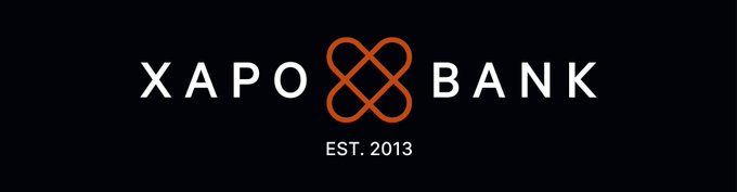 The image displays the Xapo Bank logo, featuring the brand name "XAPO BANK" in white text alongside an orange interlocking knot emblem, with "EST. 2013" underneath, all set against a black background.

This logo serves as the visual branding for Xapo Bank, the partner institution collaborating on the "Crypto Bear Market Survival Guide" for BTC holders.