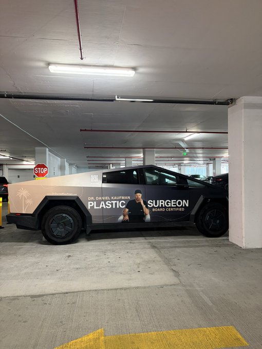 A Tesla Cybertruck parked in a garage features an advertisement for 'Dr. Daniel Kaufman Plastic Surgeon' with the word 'SURGEON' prominently displayed.