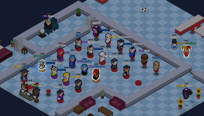 An isometric view of a 2D multiplayer online game (Habbo Hotel-style) showing numerous pixelated avatars gathered in a room with various usernames visible.