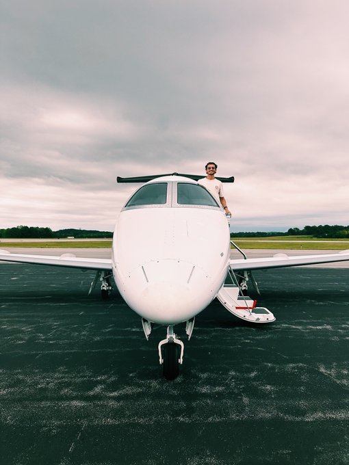 A pilot stands proudly in the cockpit of a small white private jet parked on the tarmac under a cloudy sky, celebrating a getaway with friends. The image embodies the post's message of enjoying life while maintaining financial discipline, symbolizing the rewards of low leverage and smart investment choices.
