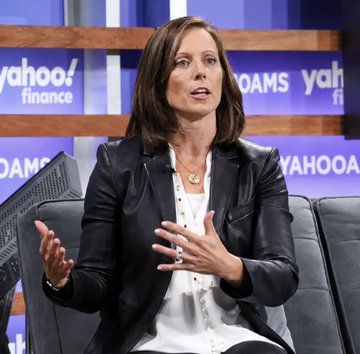 A woman in a black leather jacket gestures while speaking on a stage with a 'Yahoo Finance' backdrop visible behind her.