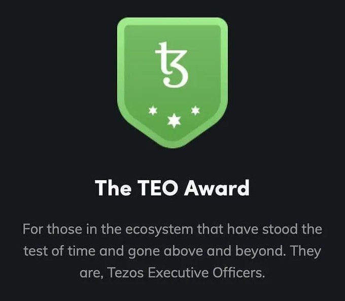The image features a green shield with white text that reads "THE TEZOS AWARD". Below the shield, there's a block of text that congratulates those who have been nominated by Tezos. The text states that the award is for those in the ecosystem that has stood the test of time and gone above and beyond to meet the needs of the community. It also mentions that the Tezos Executive Officers are being recognized for their contributions.